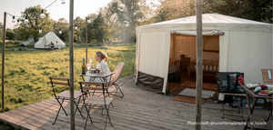 Woman sitting drinking wine outside of glamping yurt